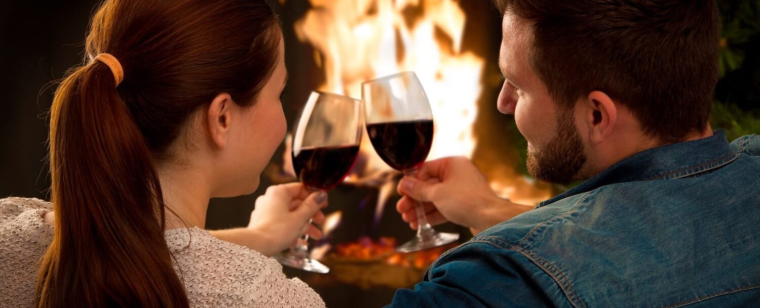 Couple drinking wine in front of a fire