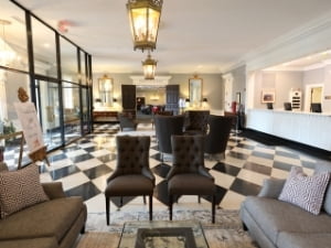 Natural Bridge Hotel lobby with glass doors, large furniture and front desk, and black and white tiled floors